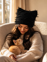 Woman wearing the black distressed crochet cat-ear beanie snuggling a kitten